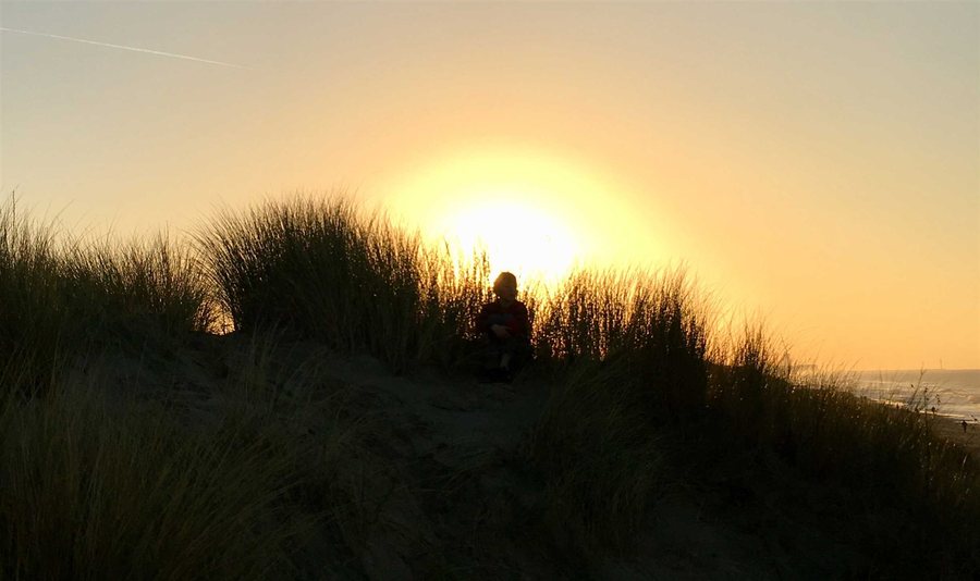 Een jongere geniet van de zonsondergang in de duinen